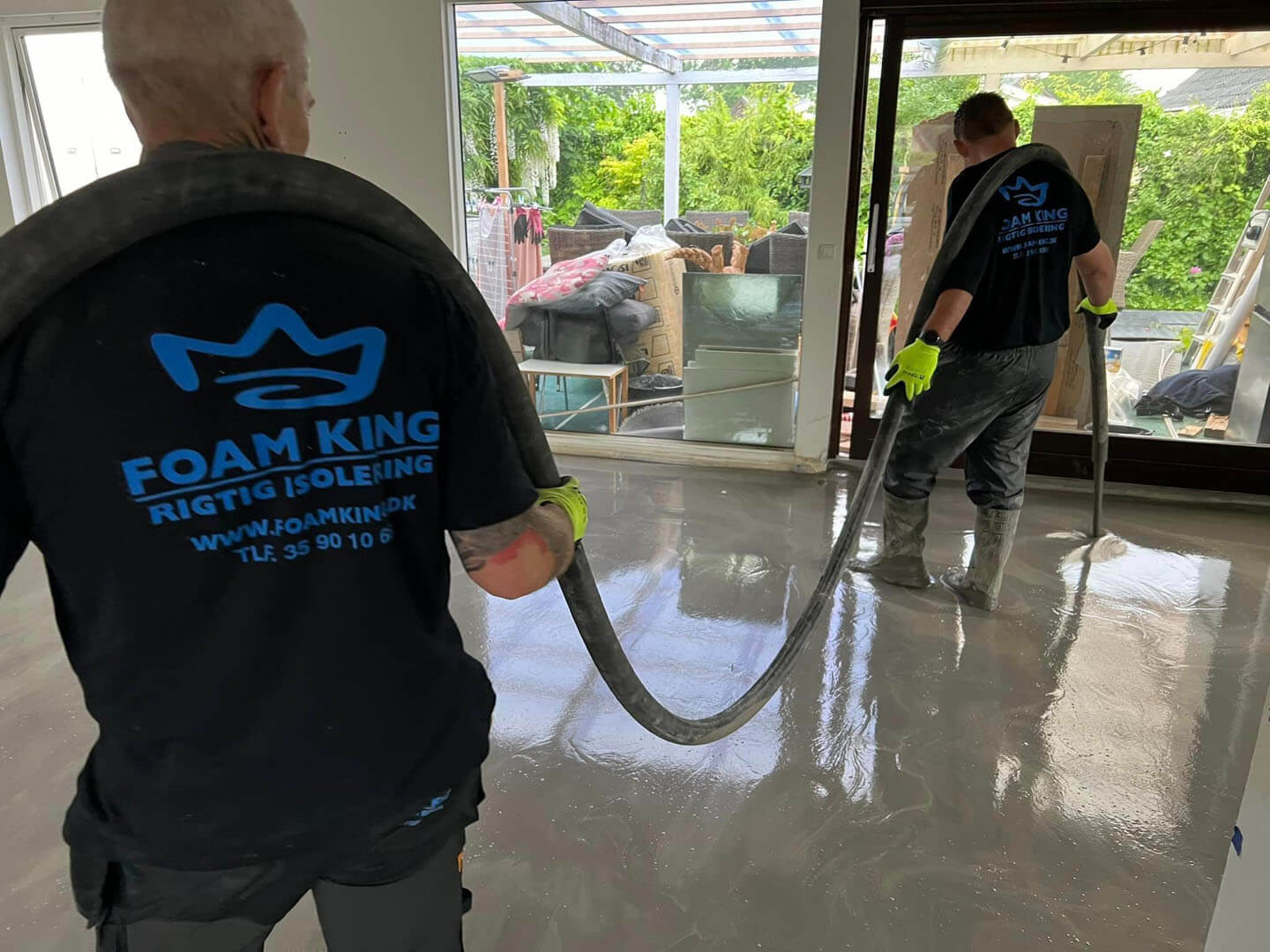 To FoamKing-medarbejdere med synligt logo på trøje under gulvmørtel-støbning